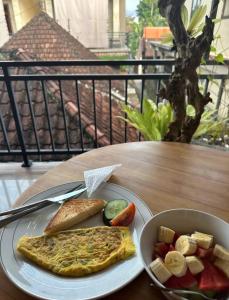 une assiette d'omelette et un bol de nourriture sur une table dans l'établissement Yudis Guest House, à Ubud