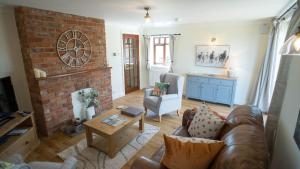 a living room with a couch and a brick fireplace at The Stables in Woodhall Spa