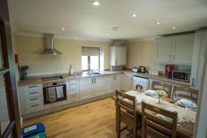 a kitchen with white cabinets and a table with chairs at The Stables in Woodhall Spa