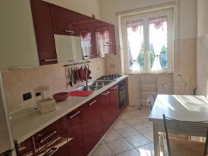 cocina con armarios rojos, fregadero y fogones en Posto al sole en Lido di Ostia