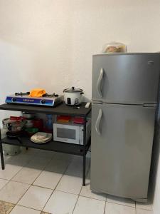a kitchen with a refrigerator and a table with a microwave at Casa Valeria Puntarenas in Puntarenas