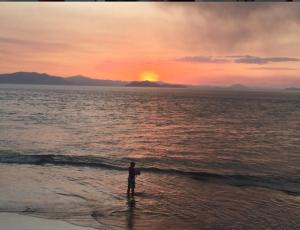 a man standing in the water on the beach at sunset at Casa Valeria Puntarenas in Puntarenas