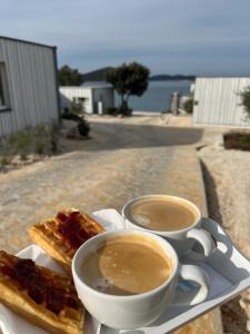 two cups of coffee and two waffles on a table at BUQEZ ECO RESORT - Beach Villas 2 and 8 - Seaview, new wifi! in Drage