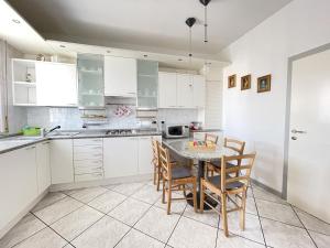 RoncofreddoにあるCa' del Monteの白いキャビネット、テーブルと椅子付きのキッチンが備わります。