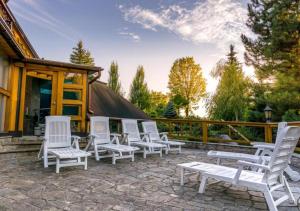 - un ensemble de chaises blanches assises sur une terrasse dans l'établissement Willa Chruślice-Basen sezon,Sauna, à Nowy Sącz