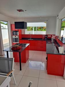 a kitchen with red cabinets and a black counter top at NAHEFLEURS in Sainte-Anne