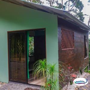 a green building with a large sliding glass door at Breezes Ecolodge in San Ramón