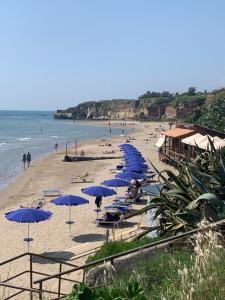 a beach with blue umbrellas and people on the beach at Anzio (RM), zona Santa Teresa in Anzio