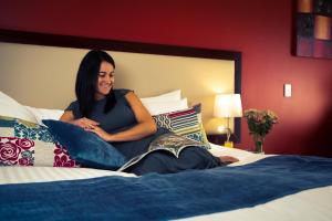 a woman sitting on top of a bed at Delorenzo Studio Apartments in Nelson