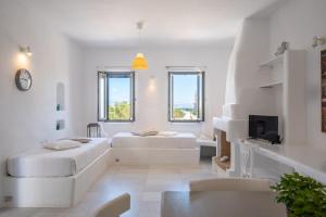een witte kamer met 2 bedden en een televisie bij Aeraki Villas in Santa Maria