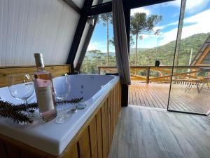 a bath tub with two wine glasses and a bottle at Pousada Recanto da Neve in Urubici