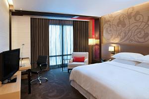 a hotel room with a bed and a desk and a television at Four Points by Sheraton Bangkok, Sukhumvit 15 in Bangkok