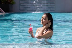a woman holding a drink in a swimming pool at Paradox Bangkok Sukhumvit in Bangkok