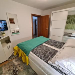 una camera da letto con un letto con una coperta verde sopra di Hana Superior Apartments a Bihać