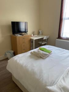 a bedroom with a bed and a desk and a television at Glory House in Ilford