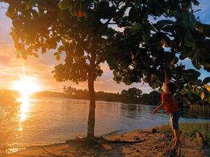 a person standing under a tree near a body of water at Residencial Lucernaré - Tiririca in Itacaré