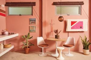 um quarto cor-de-rosa com uma mesa, cadeiras e plantas em MOOD HAUS by DW em San Juan