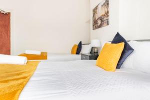 1 dormitorio con 2 camas blancas con almohadas amarillas en Home Near Anfield and Everton FC with FREE Parking, en Liverpool