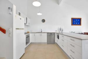 una cucina bianca con armadietti e elettrodomestici bianchi di 19 Peregian Court Resort a Peregian Beach Altre 4 foto