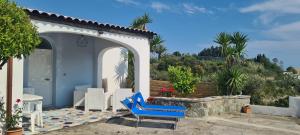 une terrasse avec une chaise bleue et une maison dans l'établissement Casa Colomba Sant'Angelo, à Ischia