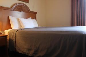 a hotel room with a bed with white pillows at Heritage Inn and Suites in Amory