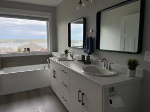 ein Badezimmer mit zwei Waschbecken, einer Badewanne und einem Spiegel in der Unterkunft Ocean View Oasis in Campbell River