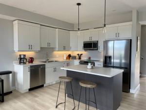 Eine Küche mit weißen Schränken und einer Kücheninsel mit Barhockern in der Unterkunft Ocean View Oasis in Campbell River