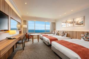 a hotel room with two beds and a table at Hotel New Akao in Atami