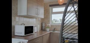 a kitchen with a microwave and a sink and a window at Seadell 2 Bed Coastal Chalet in Hemsby Great Yar in Hemsby