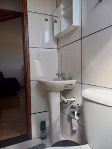 a bathroom with a white sink and a toilet at Chales Horizonte das Pedras in São Thomé das Letras