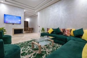 sala de estar con sofá verde y TV en Appartement spacieux avec piscine à Dar Bouazza - Casablanca, en Casablanca
