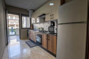 een keuken met een koelkast en een fornuis top oven bij Appartement spacieux avec piscine à Dar Bouazza - Casablanca in Casablanca