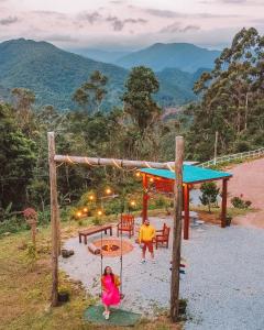 2 personnes jouant sur une aire de jeux avec des montagnes en arrière-plan dans l'établissement Cabanas Românticas em meio a Natureza - Anitápolis/SC - CB05, à Annitapolis