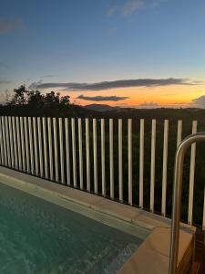 a swimming pool with a fence and a sunset at Kazadoli in Bois-Neuf
