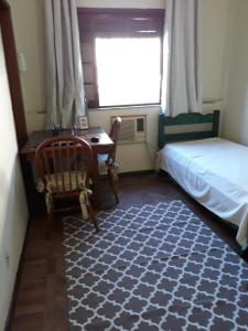 een slaapkamer met een bed, een bureau en een raam bij Bedroom near Forest in Rio de Janeiro