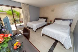 1 Schlafzimmer mit 2 Betten und einem Tisch mit einer Obstschale in der Unterkunft Casa de las Flores Hotel in Oaxaca de Juárez