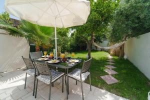 Karydakis Properties في مدينة زاكينثوس: طاولة وكراسي مع مظلة على الفناء