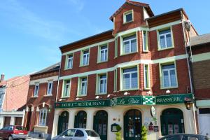 un bâtiment dans une rue avec des voitures garées devant elle dans l'établissement Hotel De La Paix, à Albert