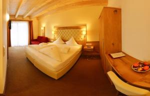ein Hotelzimmer mit einem großen Bett und einem Schreibtisch in der Unterkunft Hotel Habicht in Fulpmes