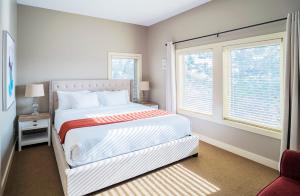 a bedroom with a large bed and two windows at Sunrise Valley Suite in West Kelowna