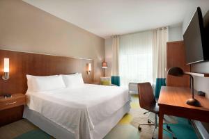 um quarto de hotel com uma cama grande e uma secretária em Four Points by Sheraton Miami Airport em Miami
