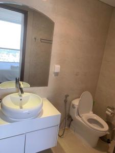 a bathroom with a sink and a toilet and a mirror at Vinhomes Central Park Apartment Landmark Căn hộ DV in Ho Chi Minh City