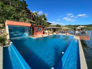 a large swimming pool next to a body of water at Pousada e Restaurante Mangue Seco Angra in Angra dos Reis