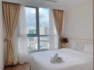 a bedroom with a white bed and a large window at Vinhomes Central Park Apartment Landmark Căn hộ DV in Ho Chi Minh City