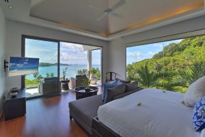 a bedroom with a large bed and large windows at Luxury Villa in Cape Panwa in Panwa Beach