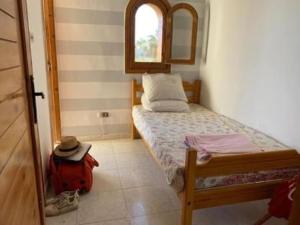 a small bedroom with a bed and a red bag at Beit Rumi in El Alamein