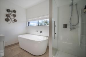 baño blanco con bañera y ventana en Million Dollar View - Takamatua Holiday Home, en Akaroa