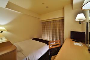 a hotel room with a bed and a desk with a television at Canal City Fukuoka Washington Hotel in Fukuoka