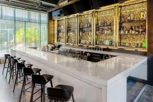 a bar with a row of stools in a room at Aloft Jacksonville Tapestry Park in Jacksonville