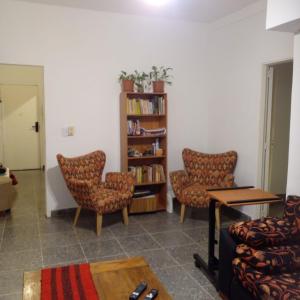 a living room with two chairs and a book shelf at Departamento en Tigre centro in Tigre +14 photos